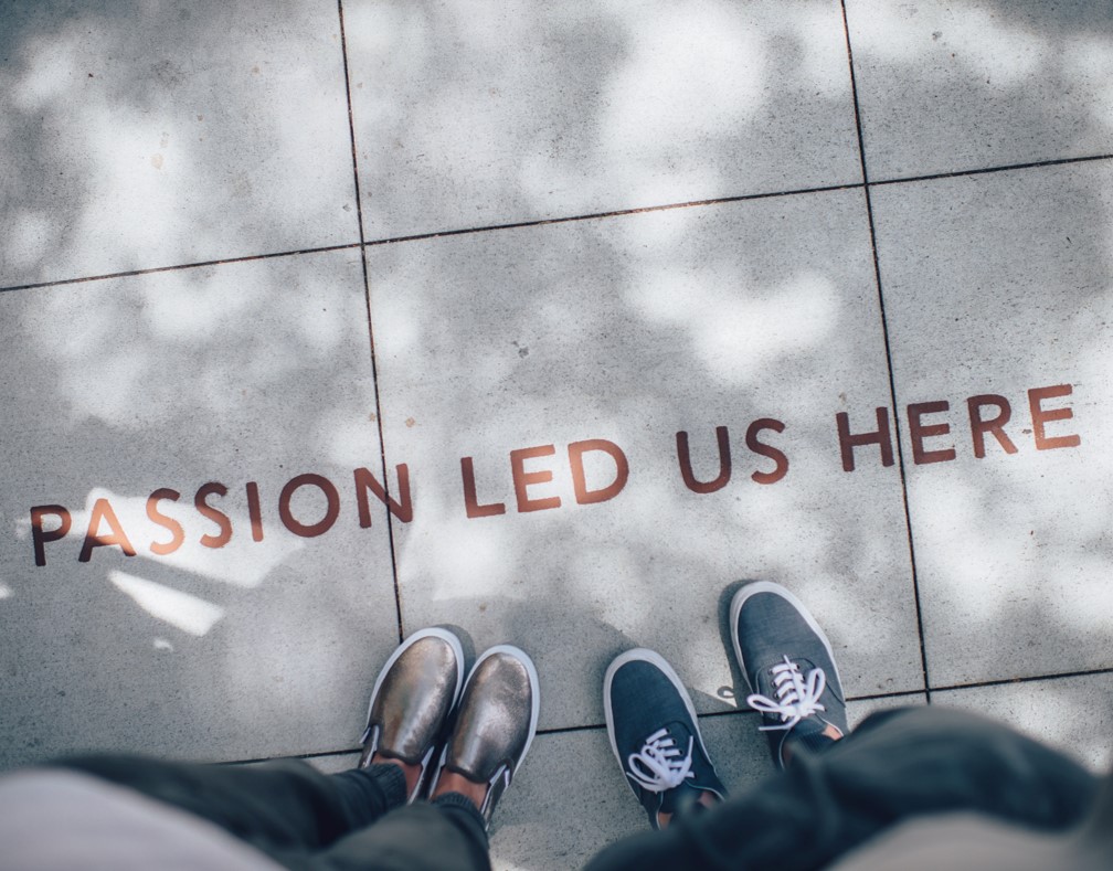 ‘Passion led us here’ written on the floor tiles and two people are standing near the writing captured from above