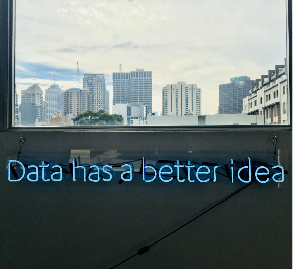 A window overlooking skyscrapers and ‘Data has a better idea’ written with neon lights under the window sill